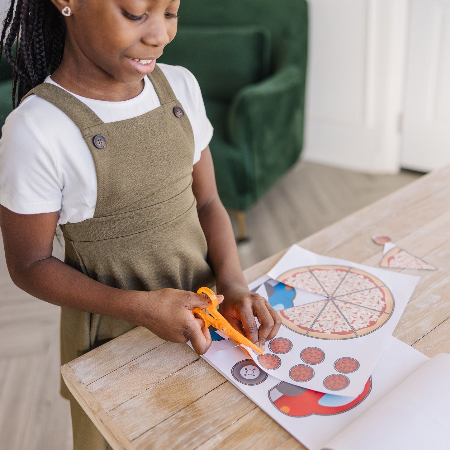 A kid playing with The Melissa & Doug Scissor Skills Activity Book With Pair of Child-Safe Scissors (20 Pages)
